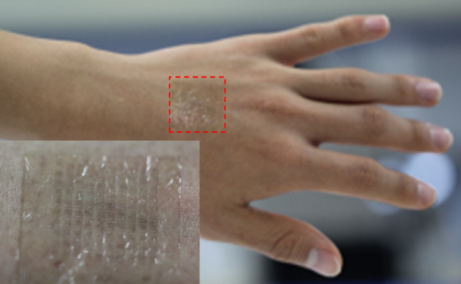 Above image shows a photograph of the transparent wireless sensor attached to the human skin.