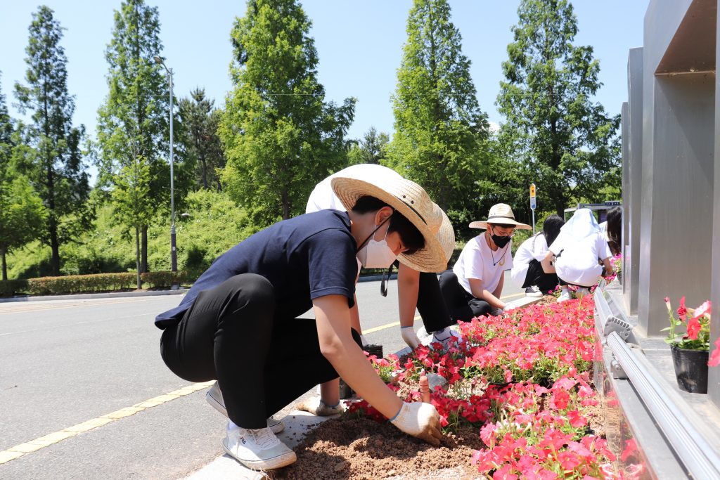 Participants generously donated their time to plant flowers in designated landscaping beds across campus, including the access road to UNIST near the symbolic landmark of UNIST. l Image Credit: UNIST Leadership Center