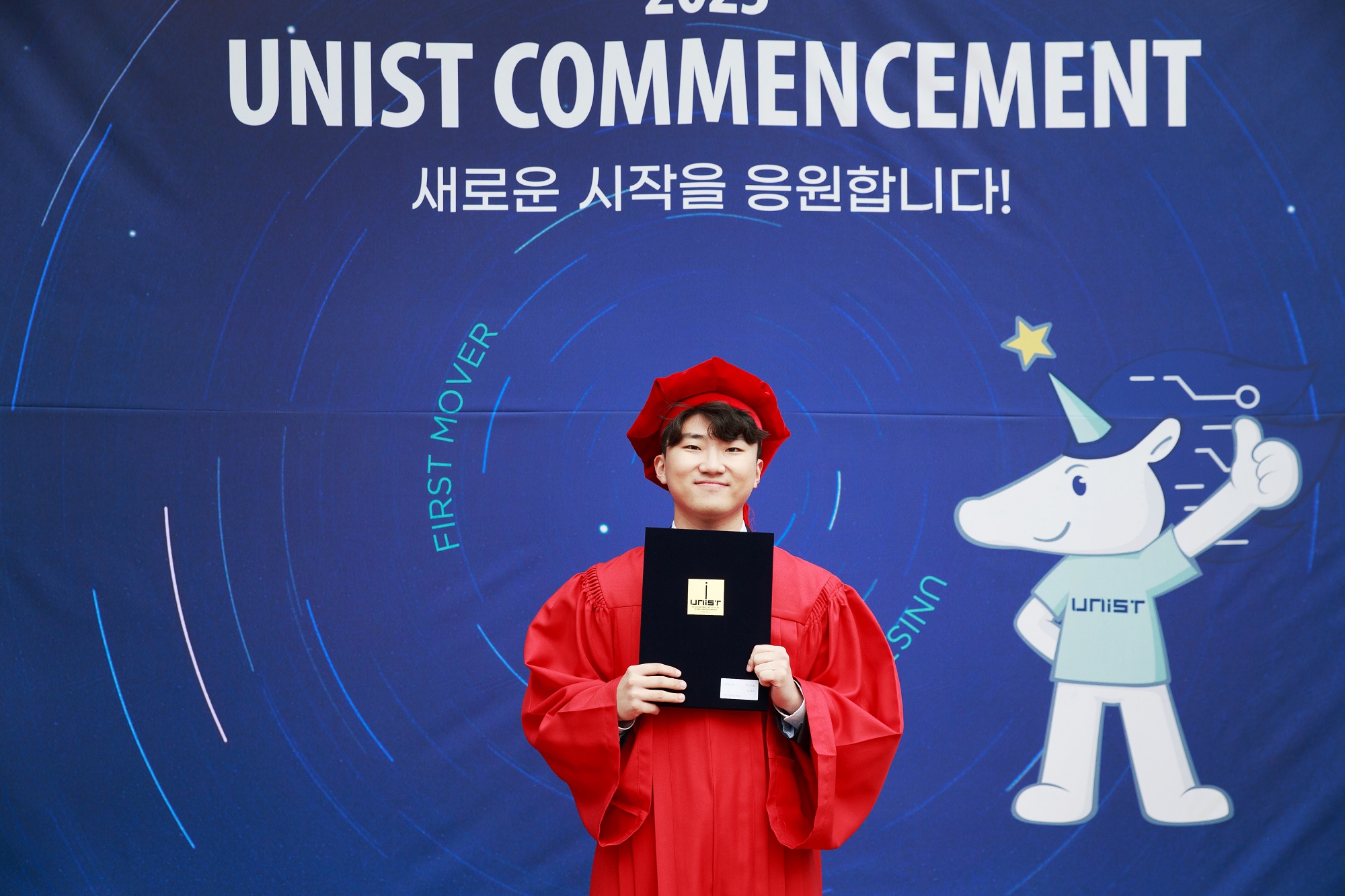 Seokju Lee (Department of Electrical Engineering) is standing in front of the photo wall at the 2023 Commencement Ceremony.
