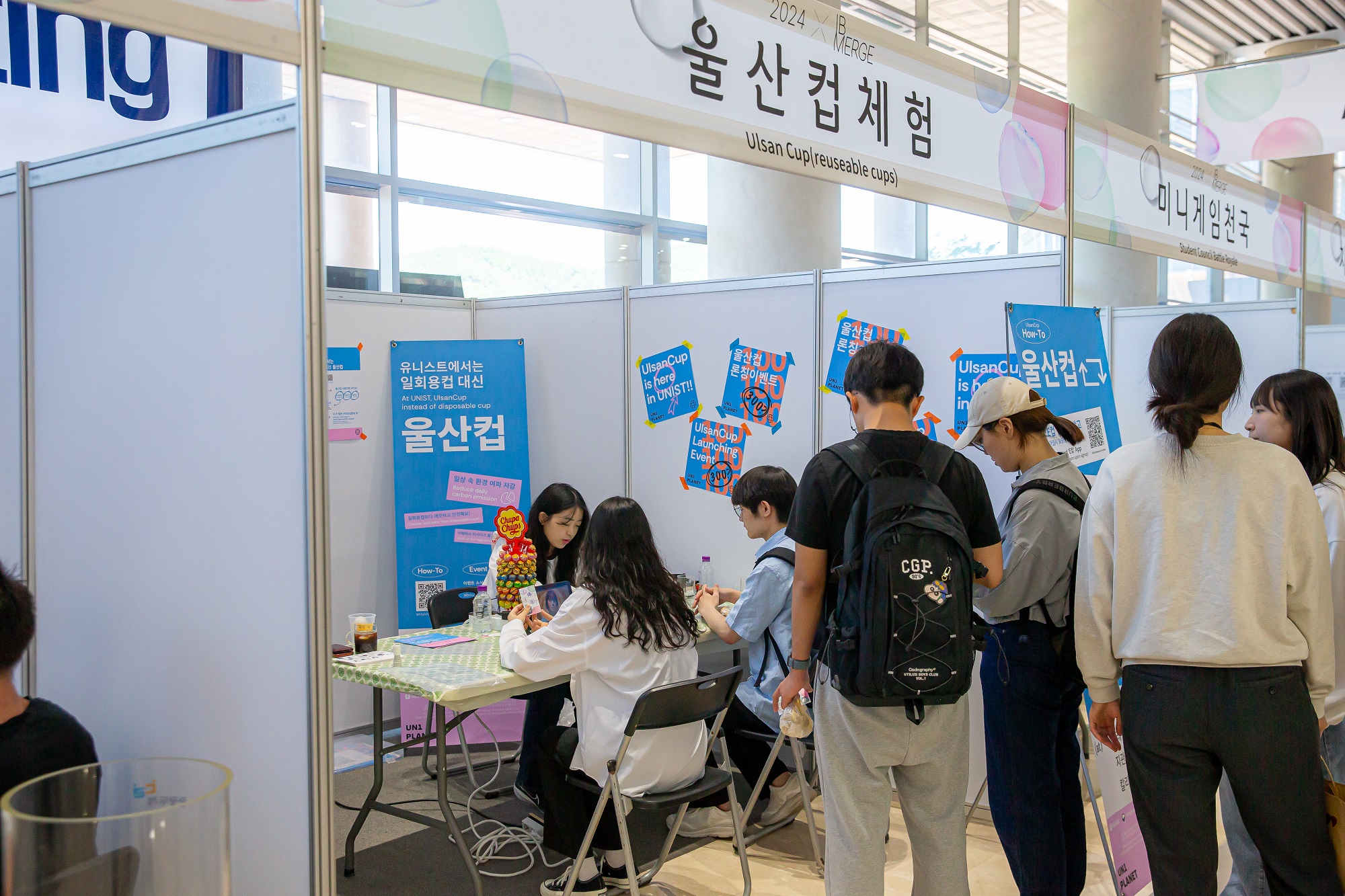 Participants at the Ulsan Cup (Reusable Cup) booth are engaged in discussions with a consultant while looking at the products on display. Image Credit: IB Academic & Student Affairs Team.