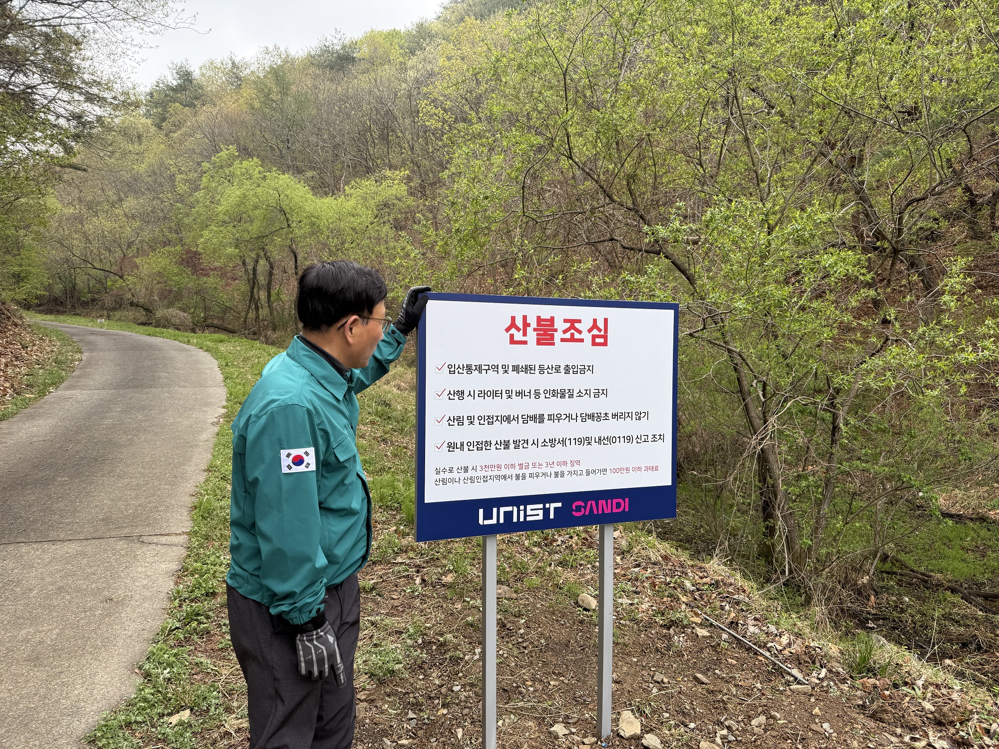 Director Yong Joon Kwon of the UNIST Safety Facility Management Division is checking the warning message on the wildfire prevention sign.