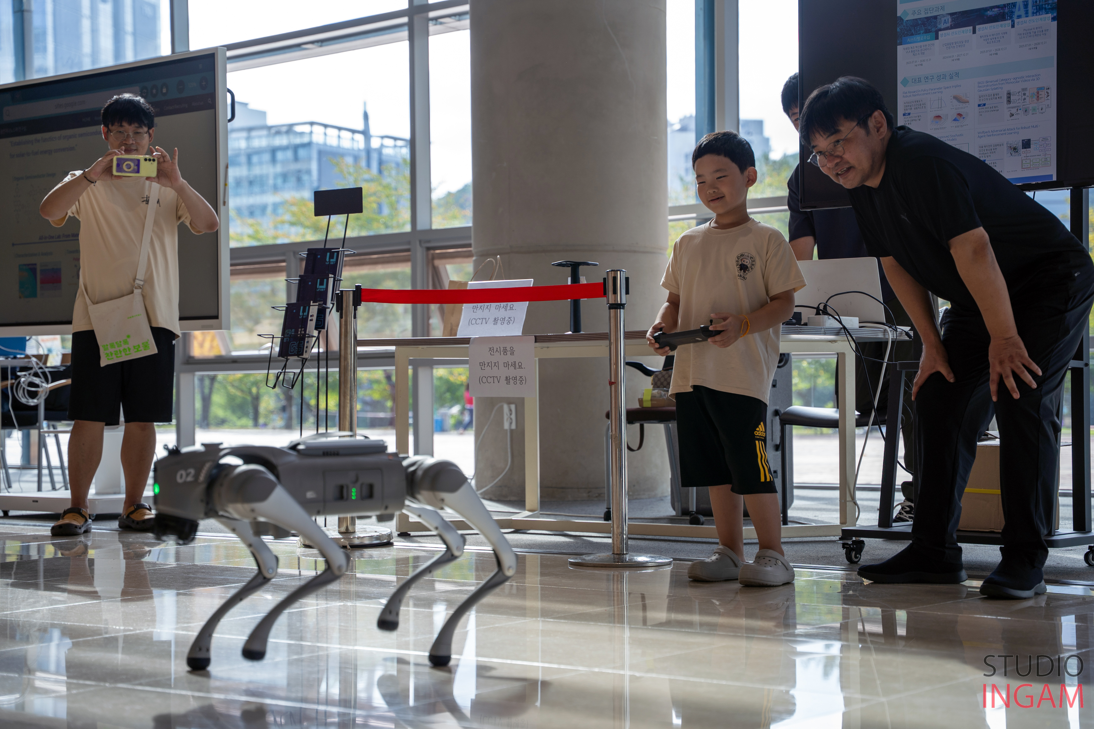A young child is operating an AI robot dog at a science experience booth, demonstrating hands-on engagement with AI technology.