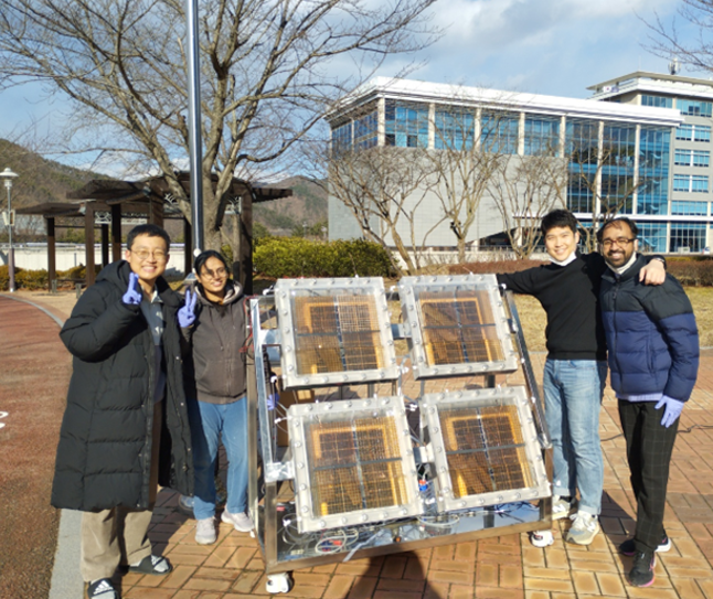 Dr. Hansora (far right) celebrates a research milestone with colleagues in front of a solar hydrogen panel at UNIST.